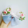 Handmade bow with detailed flower stitching.